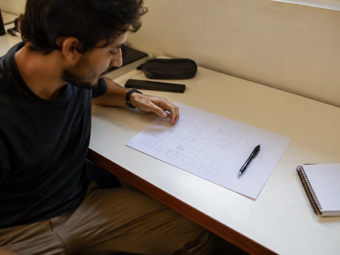 Duas participantes relendo anotações num tablet apoiado sobre a mesa de madeira